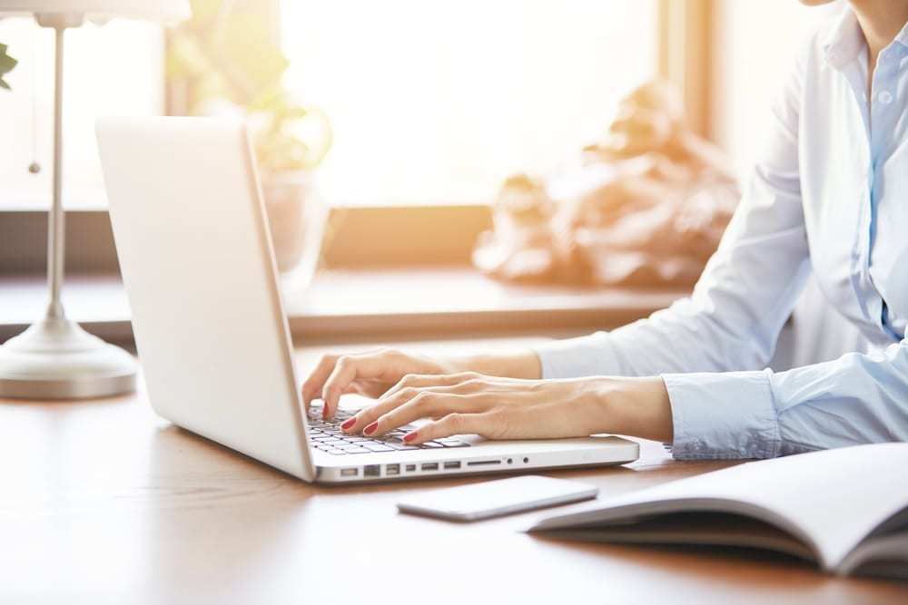 cropped photo of young woman typing on laptop