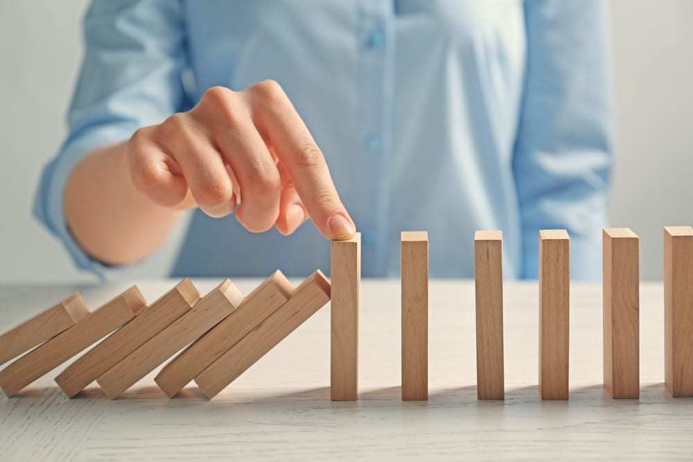 Female hand preventing domino from falling