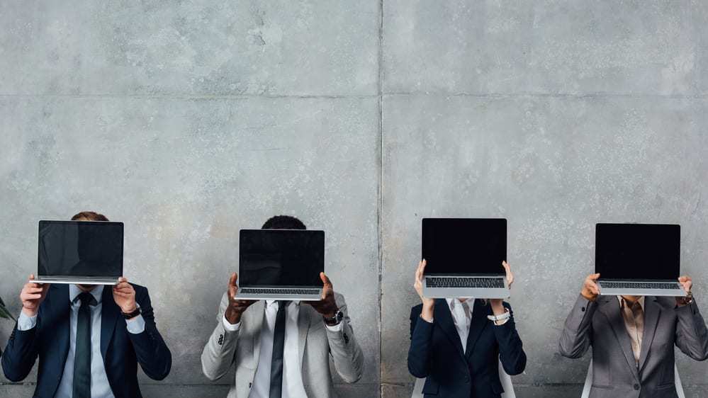 Four figures sitting and holding laptops