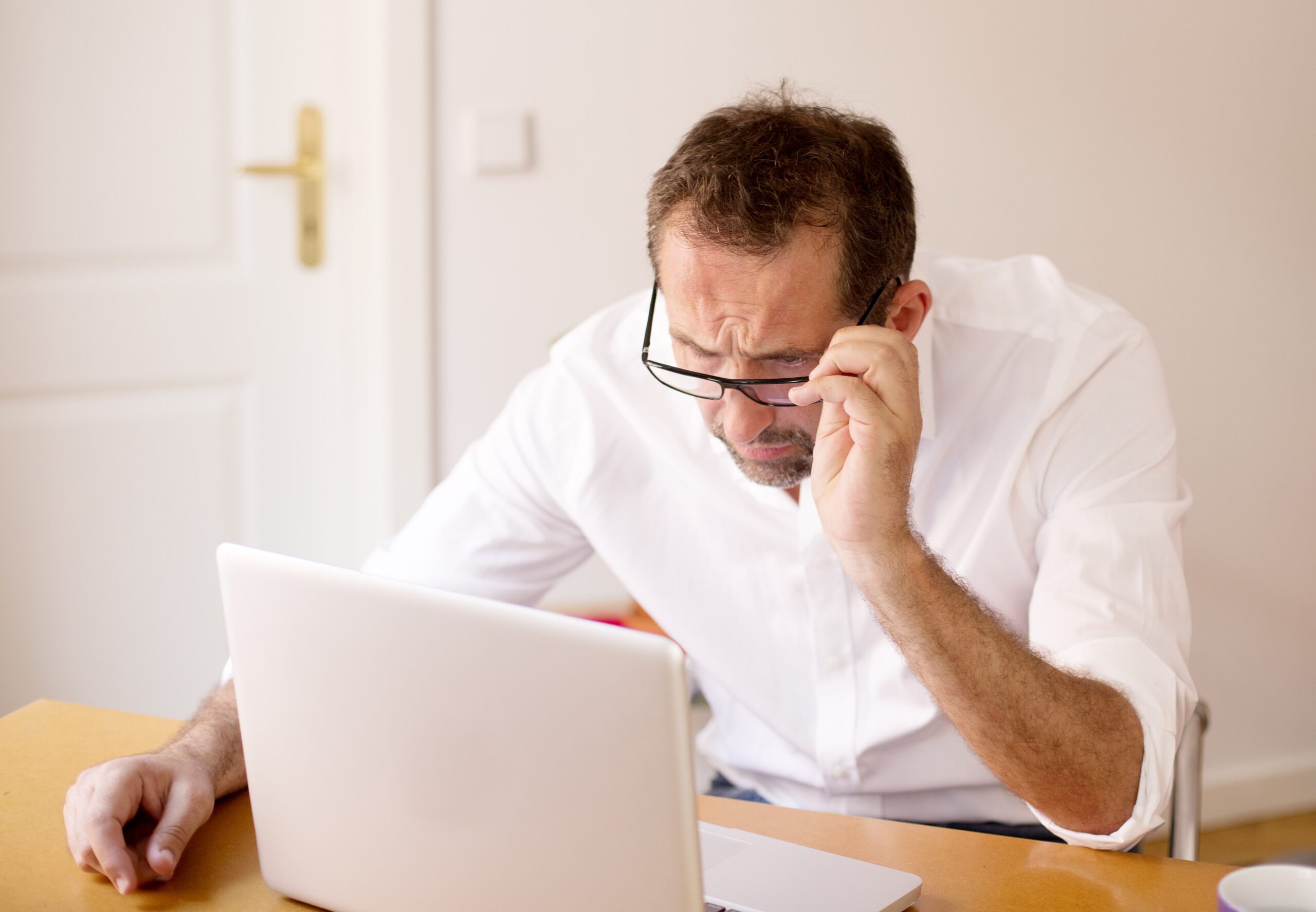Man squinting at laptop, confused